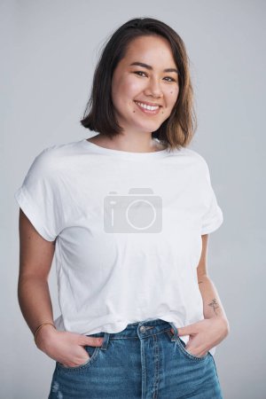 Téléchargez les photos : Portez-vous avec un sourire. une belle jeune femme posant sur un fond gris - en image libre de droit