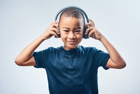 Foto de Los buenos sonidos te hacen sentir bien. Captura de estudio de un niño lindo usando auriculares contra un fondo gris - Imagen libre de derechos