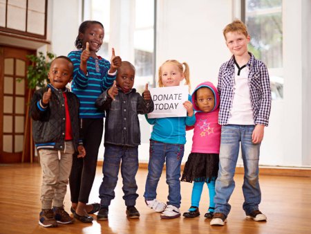 Foto de Haz nuestro día. un grupo de niños sosteniendo un signo de donación hoy - Imagen libre de derechos