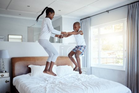 Foto de La felicidad es tener una familia unida. Retrato completo de un adorable niño jugando con su hermana en una cama en casa - Imagen libre de derechos