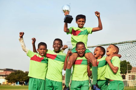 Téléchargez les photos : Le trophée est à nous. Portrait d'une équipe de soccer de garçons célébrant leur victoire sur un terrain de sport - en image libre de droit