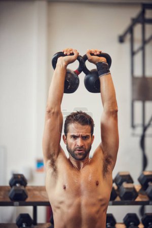 Foto de Dando este último pedacito mi todo. un joven guapo haciendo ejercicio con campanas de caldera en el gimnasio - Imagen libre de derechos