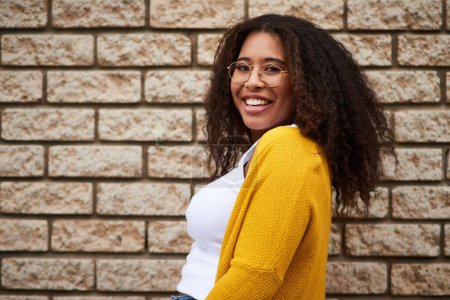Photo for Happiness lives in me. Cropped portrait of a happy young woman posing against a brick wall - Royalty Free Image