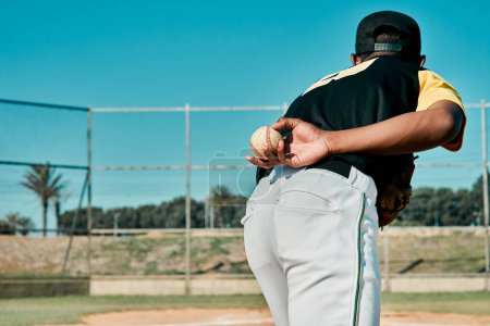 Foto de Esto arreglará la cuenta. Vista trasera de un jugador de béisbol sosteniendo la pelota detrás de su espalda - Imagen libre de derechos