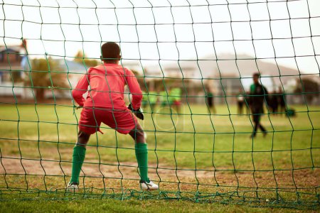 Photo for Will he be able to block the shot. Rearview shot of a young boy standing as the goalkeeper while playing soccer on a sports field - Royalty Free Image