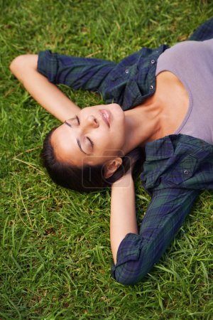 Téléchargez les photos : L'herbe verte de la maison. Plan grand angle d'une jolie jeune femme allongée sur l'herbe - en image libre de droit