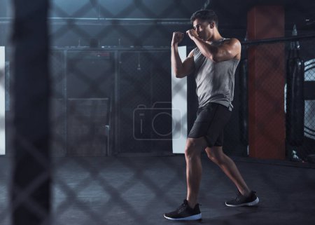 Foto de Lucha por la aptitud que te mereces. un joven practicando su rutina de kickboxing en un gimnasio - Imagen libre de derechos