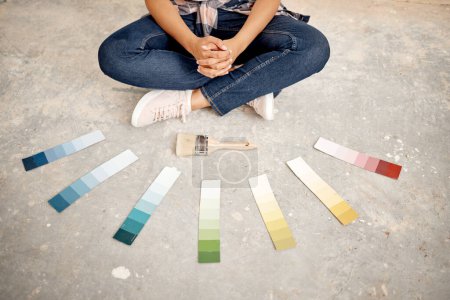 Foto de ¿Puedes ayudarme a decidir un color? una mujer irreconocible sentada en el suelo con un pincel y muestras de color - Imagen libre de derechos