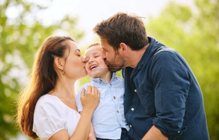Téléchargez les photos : Un baiser pour notre mignonne. une jeune famille passe du temps ensemble au parc - en image libre de droit