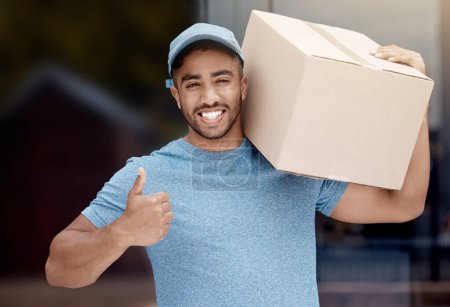 Photo for Number one in the business. Portrait of a young delivery man showing thumbs up while holding a box - Royalty Free Image