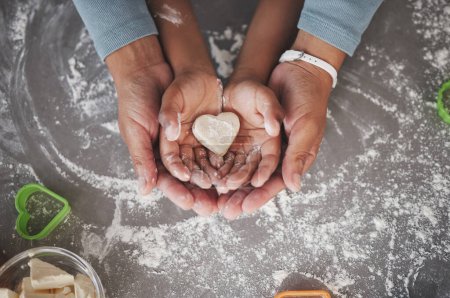 Photo for Cookies are made of butter and love. an unrecognizable girl and her mom holding a heart shaped cookie in the kitchen at home - Royalty Free Image