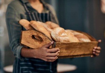 Téléchargez les photos : Étaient le pain à votre sauce. une femme tenant une sélection de pains fraîchement cuits dans sa boulangerie - en image libre de droit