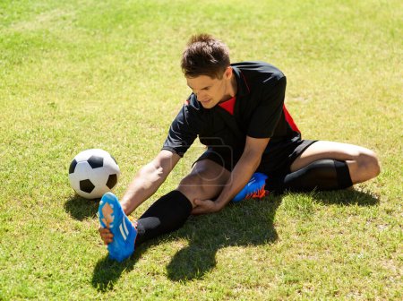 Photo for Stretching before the match. a young footballer stretching on the field - Royalty Free Image