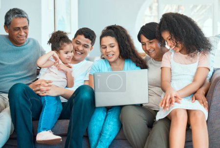 Téléchargez les photos : La famille ne perd jamais sa magie. une belle famille utilisant un ordinateur portable tout en collant sur un canapé à la maison - en image libre de droit
