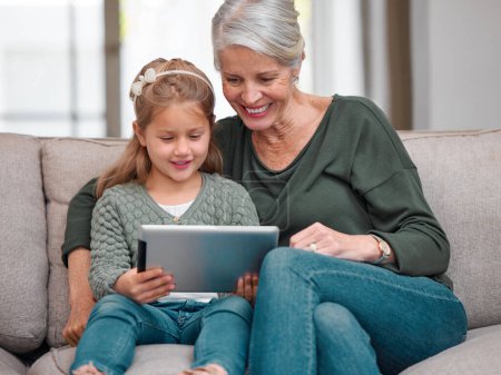 Photo for I can see why you love this show. a grandmother and granddaughter bonding on the sofa while using a digital tablet - Royalty Free Image