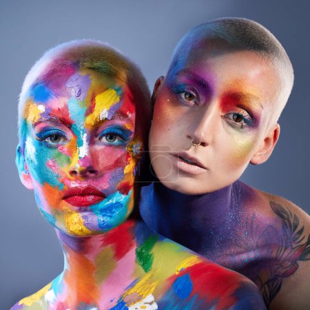 Foto de Dale color a tu vida. Foto de estudio de dos mujeres jóvenes posando con pintura multicolor en la cara - Imagen libre de derechos