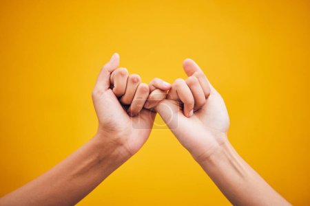 Photo for People, hands and pinky promise in studio with trust, help or hope for reconciliation on yellow background. Finger, emoji and deal by friends with secret, gesture and support expression or solidarity. - Royalty Free Image