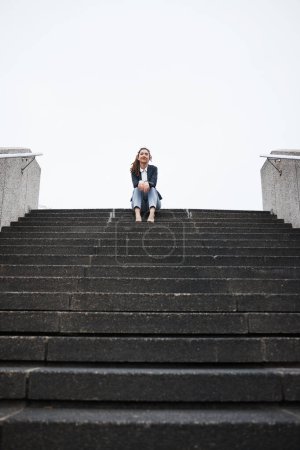 Photo for Business woman, sitting and stairs in portrait, low angle and mockup space in city, metro and relax on break. Young entrepreneur, urban cbd and freedom on steps with corporate fashion, pride or smile. - Royalty Free Image