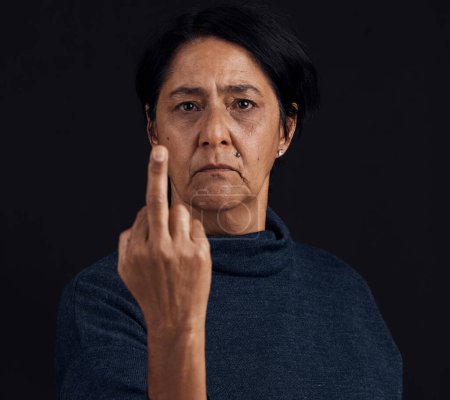 Photo for Portrait, anger and senior woman with middle finger, opinion and expression on a black studio background. Face, female person and old model with gesture, rude and frustrated with problem and conflict. - Royalty Free Image
