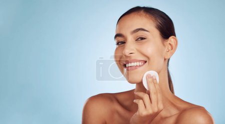 Photo for Happy woman, portrait and cotton pad for skincare or makeup removal against a blue studio background. Female person or model smile with swab for cosmetics, foundation or facial treatment on mockup. - Royalty Free Image