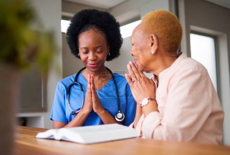 Photo for Healthcare, black woman nurse and patient praying together while reading the bible in an old age home. Medical, trust or faith with a female medicine professional and senior adult talking to God. - Royalty Free Image