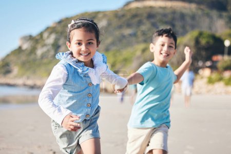 Téléchargez les photos : Enfants, frère et sœur courant à la plage, portrait et se tenant la main avec sourire, aventure et vacances. Jeunes enfants, heureux et ludiques avec course, jeux et liberté par l'océan pour l'été à Hawaï. - en image libre de droit