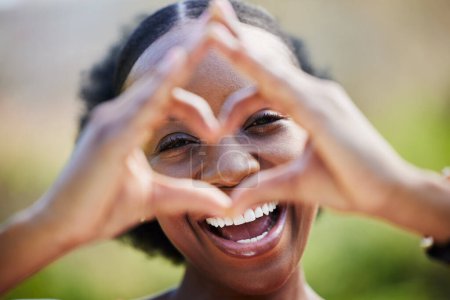 Téléchargez les photos : Heureuse femme noire, portrait et visage avec les mains du cœur pour l'amour, les soins ou le bien-être sain dans la nature. Femme africaine sourire avec comme emoji, symbole ou icône et geste de la main pour la romance à l'extérieur. - en image libre de droit