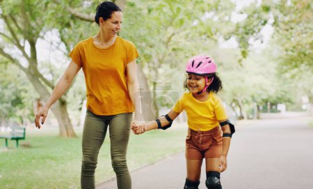 Photo for Mom, park and holding hands to rollerskate with child with care, learning and support. Interracial parent, teaching and woman with girl kid, smile and helping hand on road for skating on vacation. - Royalty Free Image