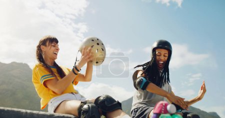 Foto de Rollerskate, skatepark y diversión con un par de amigos sentados al aire libre en una rampa para la recreación juntos. Aptitud, diversidad o deportes con un hombre y una mujer que se unen al aire libre para un hobby activo. - Imagen libre de derechos