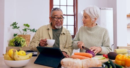 Photo for Senior couple, cooking and tablet in kitchen with knife, vegetables and tea cup for conversation. Interracial marriage, elderly woman and old man with touchscreen for app, food or nutrition in home. - Royalty Free Image