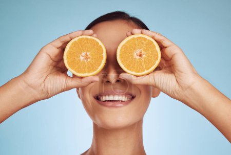 Photo for Happy woman, eyes and orange for natural vitamin C, skincare or diet against a blue studio background. Face of person smile with organic citrus fruit for nutrition, dermatology or healthy wellness. - Royalty Free Image