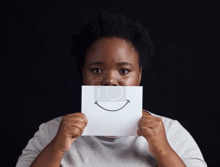 Photo for Paper smile, portrait and a black woman on a studio background for mental health, problem or fear. Advertising psychology, poster and the face of an African patient or girl with bipolar or sad. - Royalty Free Image