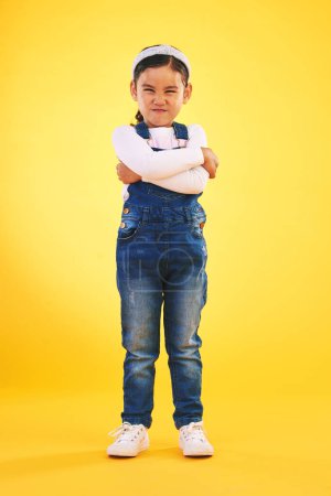 Photo for Arms crossed, angry and portrait of girl child in studio with bad, attitude or behavior problem on yellow background. Frown, face and asian kid with body language for no, frustrated or tantrum emoji. - Royalty Free Image