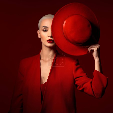 Photo for Portrait, fashion and a model woman on a red studio background for elegant or trendy style. Aesthetic, art and beauty with a young female person looking edgy or classy in a suit or unique clothes. - Royalty Free Image