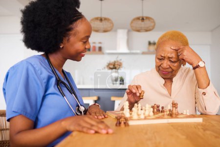 Foto de Los negros, las enfermeras y el pensamiento en los ancianos cuidan el ajedrez, la diversión o la actividad social juntos en casa. Africano profesional médico jugando juego de mesa de estrategia con la persona mayor femenina en la casa. - Imagen libre de derechos