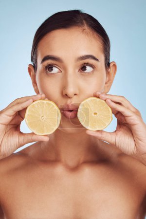 Photo for Woman, hands and lemon for skincare detox, diet or collagen against a blue studio background. Female person or model holding organic citrus fruit for natural nutrition, anti aging or facial treatment. - Royalty Free Image