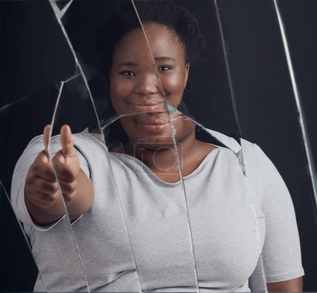 Photo for Healing, success and woman portrait with thumbs up in broken mirror after depression and stress in studio. Face, smile and African female abuse survivor emoji hand for feedback on bipolar treatment. - Royalty Free Image