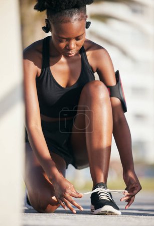 Téléchargez les photos : Femme noire, chaussures de plein air et cravate pour l'entraînement, la formation et l'exercice. Sport, fitness et athlète africain attachant des lacets sur les baskets pour commencer à courir, se préparer pour le cardio et le jogging, la santé et le bien-être. - en image libre de droit