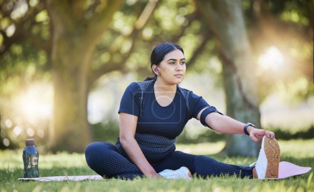 Photo for Woman, fitness stretching and nature park listening to music after a runner exercise and sports. Real plus size athlete from India stretch legs ready for wellness, health workout and running on grass. - Royalty Free Image