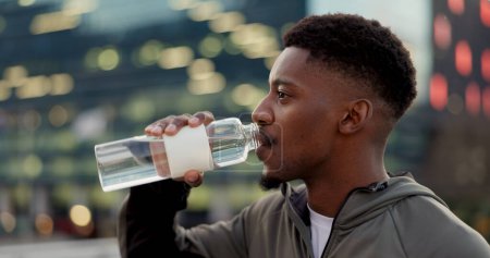 Téléchargez les photos : Homme noir, eau potable et fitness en ville après l'entraînement, l'exercice ou l'entraînement en plein air pour une durabilité naturelle. Homme africain assoiffé avec boisson minérale pendant la pause pour l'hydratation en ville. - en image libre de droit