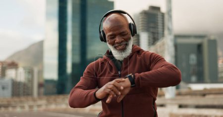 Photo for Man, headphones and smart watch in city for fitness, exercise results and workout performance. Happy senior african runner check timer, clock and healthy training progress with music in urban street. - Royalty Free Image