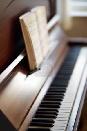 Photo for The piano. A vintage grand piano with a book of sheet music for education. An antique and classic keyboard is used to develop skills. A classical wooden musical instrument for practising music - Royalty Free Image