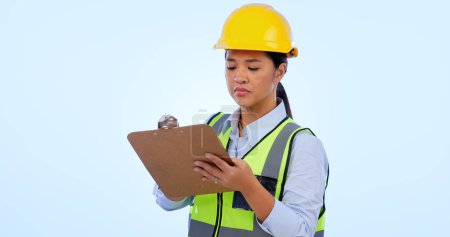 Photo for Woman engineer, inspector and checklist for construction, project management and studio by blue background. Asian female, architecture and development or real estate, plan and safety gear in mockup. - Royalty Free Image