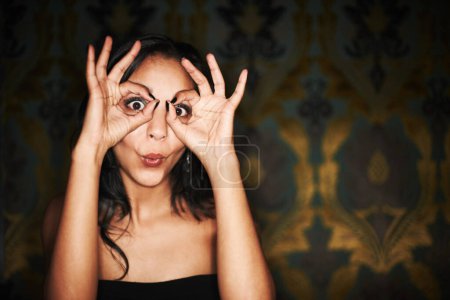 Photo for Woman, hands and ok or sign on face at club, crazy and silly or goofy, energy and funny at night. Female person, dark and comedy or humor, eyes and emoji or icon, posing and agree with yes review. - Royalty Free Image