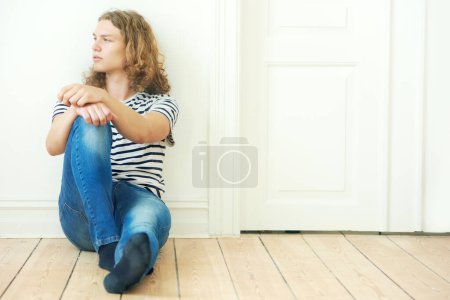 Photo for Man, thinking and fashion for sitting on floor in home for looking, vision or peace. Sweden boy, male person and alone with idea for future by contemplating with curly hair, trendy or style for teen. - Royalty Free Image
