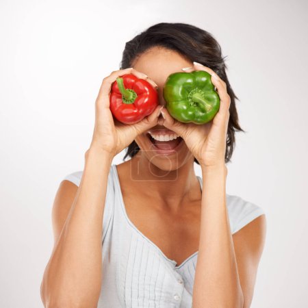 Photo for Face, green and red pepper with a woman in studio on a white background, excited about health, diet or nutrition. Hands, smile and a young person holding vegetables as ingredients for a recipe. - Royalty Free Image