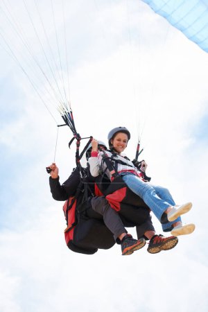 Photo for People, paragliding and smile in sky, together or extreme sport with freedom for fitness. Coach, partnership and person on adventure, helmet or fearless with backpack, parachute or portrait in clouds. - Royalty Free Image