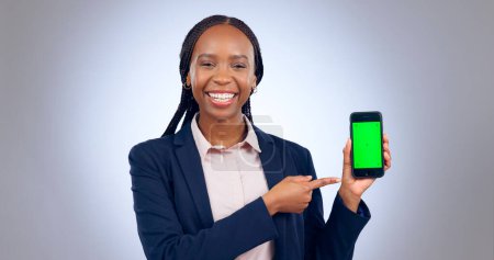 Photo for Business woman, smartphone and pointing to green screen for advertising space, offer and mockup newsletter in studio. Portrait, happy african worker and mobile announcement of deal on grey background. - Royalty Free Image