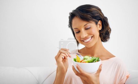 Téléchargez les photos : Femme heureuse, bol et salade pour une alimentation saine, une nutrition naturelle ou un bien-être sur le canapé du salon à la maison. Sourire féminin, végétalien ou nutritionniste pour un repas végétarien, une collation à base de fibres ou de vitamines. - en image libre de droit