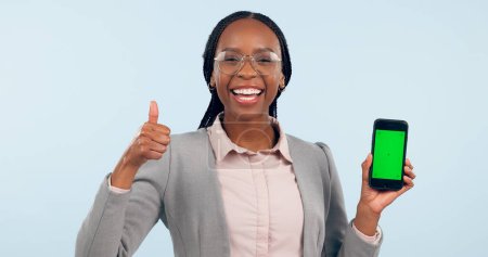 Photo for Business woman, thumbs up and green screen phone with portrait for review, choice or app by blue background. African entrepreneur, yes and studio for smartphone mockup, chromakey or tracking markers. - Royalty Free Image